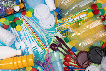 Disposable single use plastic objects such as bottles, cups, forks, spoons and drinking straws that cause pollution of the environment, especially oceans. Top view. - obrazy, fototapety, plakaty