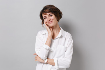 Smiling cute young business woman in white shirt posing isolated on grey background studio...
