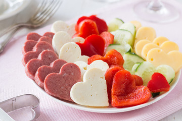 Valentine's day snack plate with cheese, red pepper, sausage, bread, cucumber