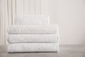 Stack of fresh towels on light grey stone table in bathroom