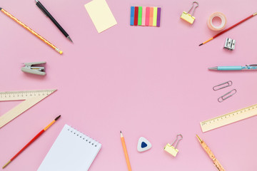 Stationary, back to school,creativity and education concept. Notebook, pen, pencil, eraser, ruler, paper clips, stapler, brush on pink background, flat lay. Top view