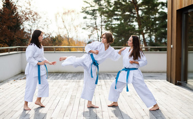 Group of young women practising karate outdoors on terrace.