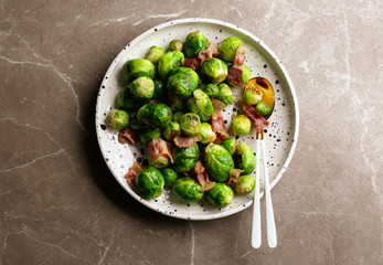 Delicious Brussels sprouts with bacon on marble table, top view