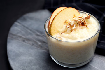 Delicious rice pudding with apple and almond on grey board, closeup. Space for text