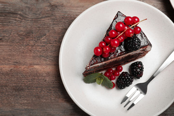 Tasty chocolate cake with berries on wooden table, top view