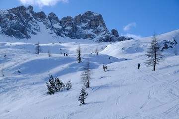 A group of skiers going on backcountry skis through snowy high mountains on a sunny day. During trip in Dolomites around Tre Cime. Sexten Dolomites, South Tyrol, Italy