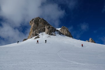 Naklejka na ściany i meble A group of skiers going on backcountry skis through snowy mountains on a sunny day. During trip in Dolomites around Tre Cime. Sexten Dolomites, South Tyrol, Italy