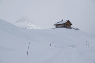 Beautiful view of lonely small wooden house in snowy mountains in foggy winter day, when all around is white. Around Alpe di Nemes refuge in Sexten Dolomites, South Tyrol, Italy