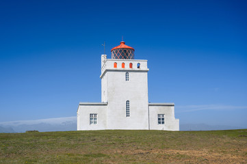 Fototapeta na wymiar Dyrholaey Lighthouse in sunny day against blue sky