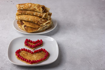 Heart-shaped pancakes decorated with berries and a plate of pancakes.