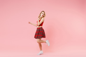 Side view of pretty young blonde woman girl in red sexy clothes posing isolated on pastel pink background studio portrait. People sincere emotions lifestyle concept. Mock up copy space. Having fun.