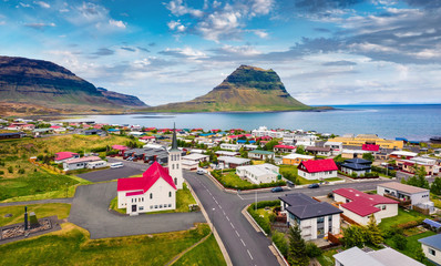 View from flying drone. Splendid morning cityscape of Grundarfjordur town with Kirkjufell Mountain on background. Aerial view of Grundarfjordur Church, Iceland, Europe. Traveling concept background.