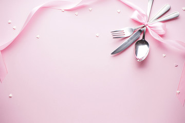 Sweet hearts and cutlery on a white plate with a pink ribbon on a pink background, flat lay. Valentine's Day. Love concept. Mother's day background.