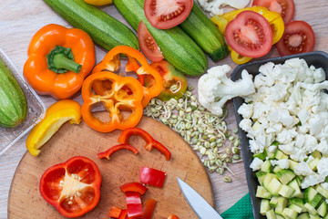 Sliced vegetables top view, tomatoes, zucchini, sweet peppers, cauliflower, bean sprouts and other ingredients on the kitchen table