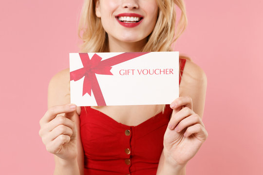 Cropped image of young blonde woman girl in red sexy clothes isolated on pastel pink background studio portrait. People sincere emotions lifestyle concept. Mock up copy space. Hold gift certificate.