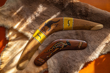 Two old boomerangs laying on the kangaroo skin, fur with wooden glossy table in the background....