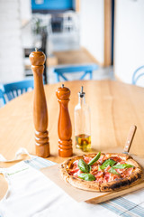 Delicious pizza stands on the table, pizza with red sauce, pancetta and basil, Italian cuisine, pizzeria