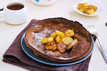 Chocolate Dutch Baby pancake with caramelized bananas on a gray plate on a light concrete background. Selective focus. American cuisine. Dessert for Valentine's Day