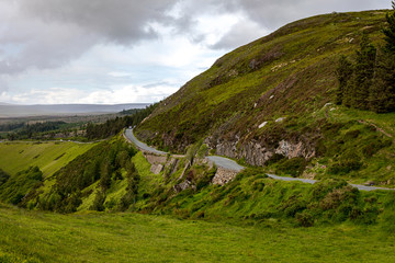 Fototapeta na wymiar Irish through the green hills under heavy cloudy sky I