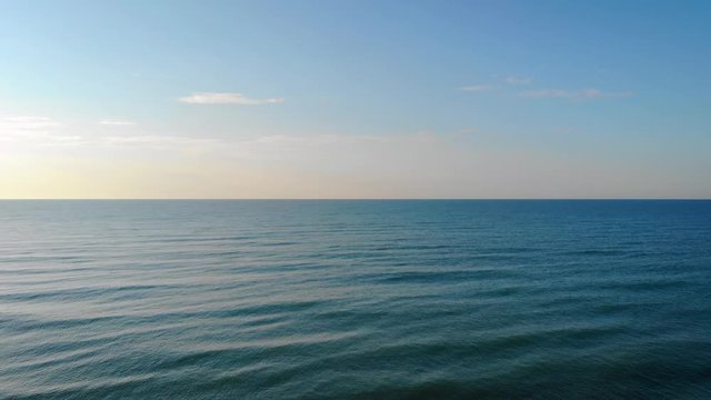 AERIAL: Fly into open waters from the beach. Waves breaking. Sunset vibes. Caorle, Italy