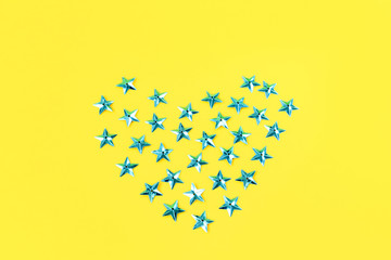 Creative festive sky blue heart from stars on a yellow background. Flat lay