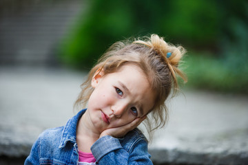 Emotions of a cunning little girl of 3 years. A close-up girl with a bun on her head and disheveled...