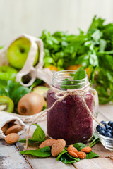 Healthy food and vegan diet concept - mason jar of fresh juice or smoothie with blueberry, spinach, banana, almond milk. Antioxidant detox beverage with raw ingredients.  Close up, wooden background.