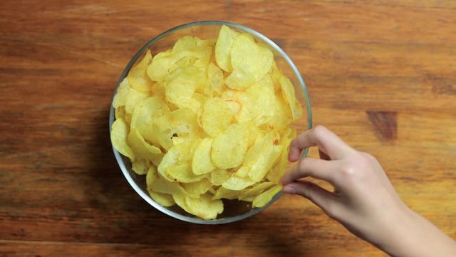 Big family eating potato chips from bowl, top view