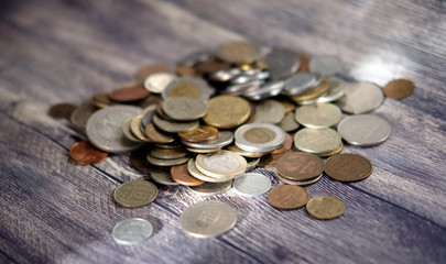 Coins from different countries on a dark wooden table