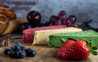 Different Dutch cheese types on plate and bread and fruit in the background