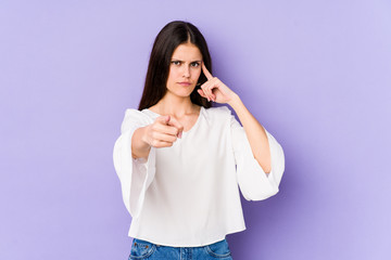 Young caucasian woman isolated on purple background pointing temple with finger, thinking, focused on a task.