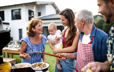 Portrait of multigeneration family outdoors on garden barbecue, grilling. - obrazy, fototapety, plakaty