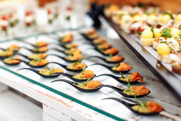 Different light snack on glass and wooden tray
