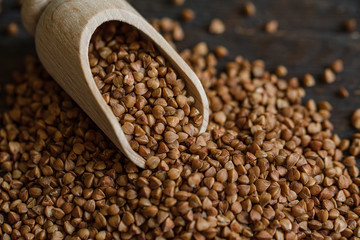 Scoop and buckwheat macro view on rustic background. Close up raw buckwheat background.