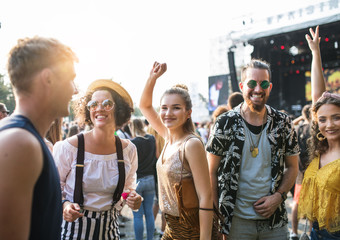 Front view portrait of group of young friends dancing at summer festival.