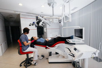 The dentist looks through a microscope and performs surgery on the patient