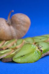Big ugly vegetable organic kiwi on a green background. Sweet fruit slices. Ugly food concept.