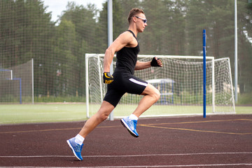 Muscular man in a t-shirt and shorts. Running in the stadium.