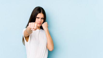 Young caucasian woman isolated on blue background throwing a punch, anger, fighting due to an argument, boxing.