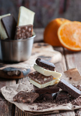 white and black chocolate on a wooden table with orange and knife