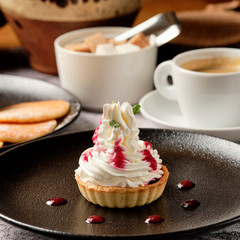 Cupcakes with whipped white vanila cream with a cup of black coffee americano for breakfast, background with copyspace. Food and drink concept.