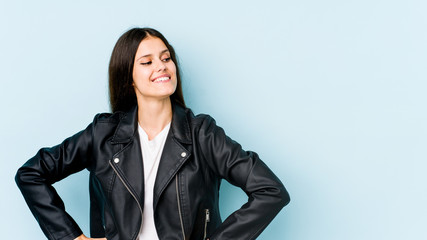 Young caucasian woman isolated on blue background laughs happily and has fun keeping hands on...