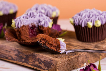 Chocolate cupcakes on a wooden table with flowers from the cremama, with fruit jam inside.