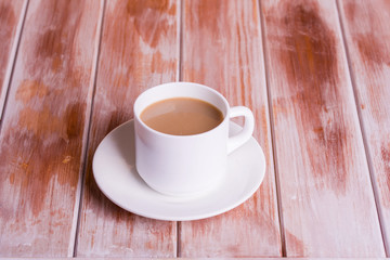 Fragrant coffee with milk on a wooden table in a white cup.