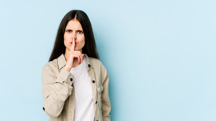 Young caucasian woman isolated on blue background keeping a secret or asking for silence.
