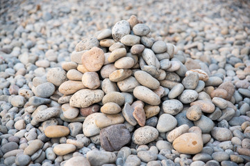 Heap of sea pebbles made by travelers on a seashore, close-up. Natural summer background with soft copy space