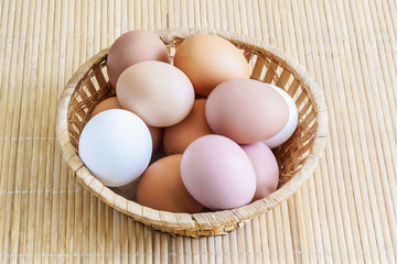 Different chicken eggs are in a basket on a wooden table. White and brown. Combination of color. Palette