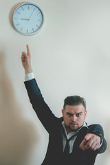 You're late! Angry businessman is pointing at  clock suggesting you are late for work.