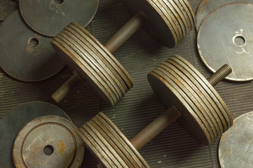 Vintage Rusty Dumbbells and Additional Plates on Scratched Rubber Floor