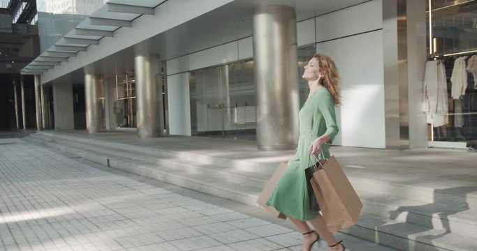 attractive happy woman leaves the store with shopping bags
